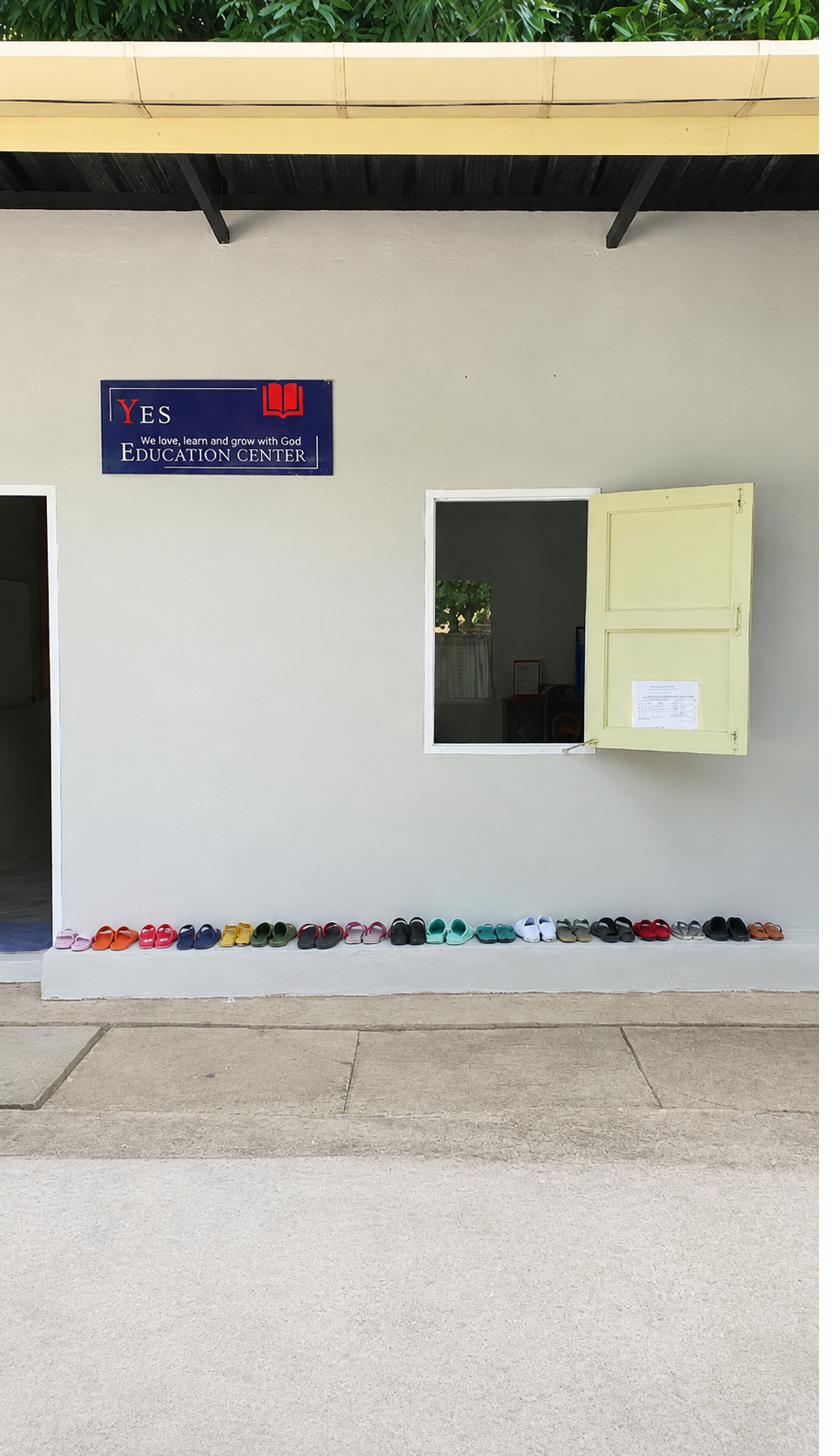 Exterior of the education center building with rows of children's shoes lined up outside the door